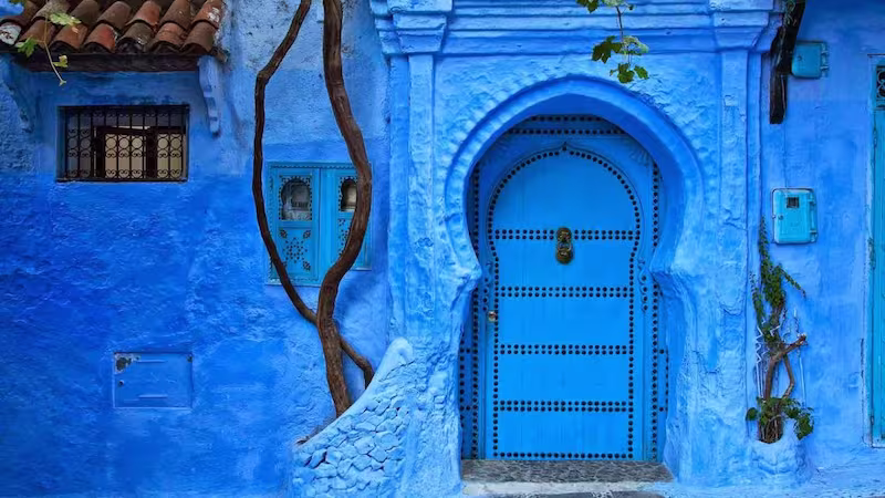 Traditional blue painted wooden door and wall in the medina of Chefchaouen, the Blue Pearl of Morocco